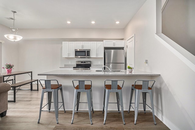 kitchen featuring white cabinetry, appliances with stainless steel finishes, a breakfast bar, and kitchen peninsula