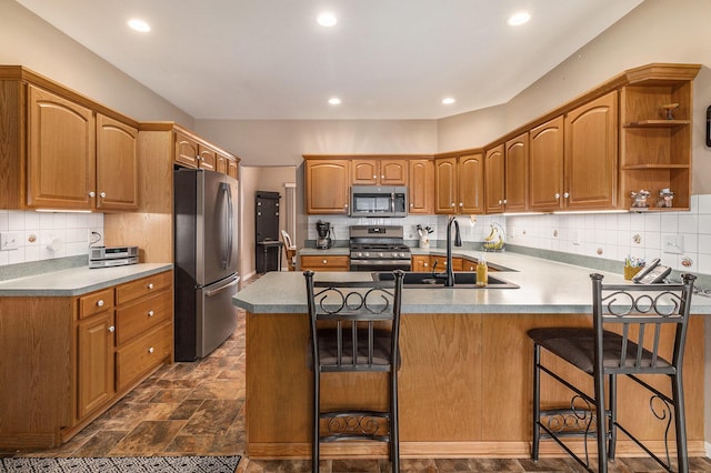 kitchen with sink, a breakfast bar, kitchen peninsula, and appliances with stainless steel finishes