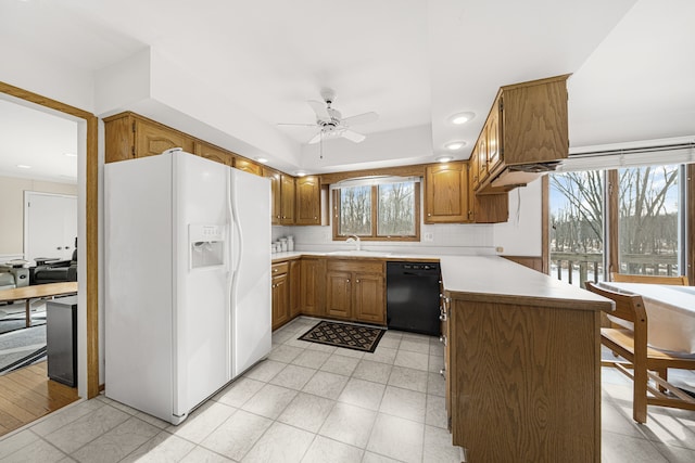 kitchen featuring sink, black dishwasher, white fridge with ice dispenser, kitchen peninsula, and decorative backsplash