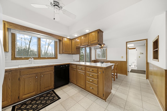 kitchen featuring sink, dishwasher, wood walls, ceiling fan, and kitchen peninsula