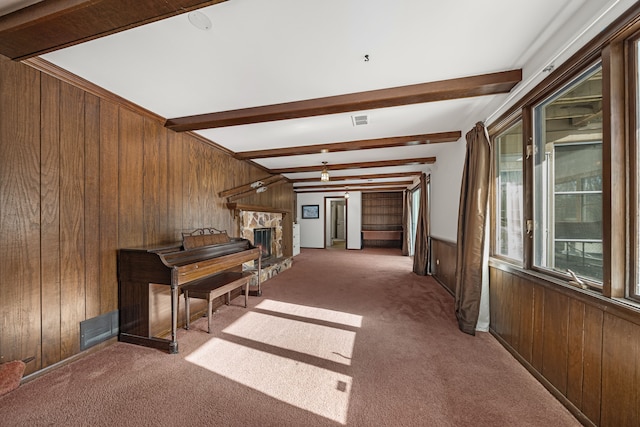 interior space featuring a fireplace, carpet floors, beamed ceiling, and wood walls