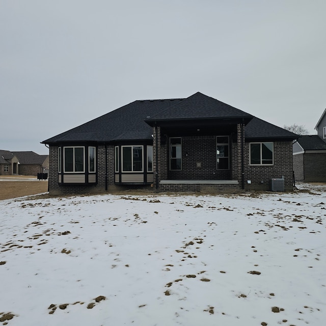 snow covered house featuring central AC unit