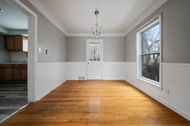 unfurnished dining area with light hardwood / wood-style flooring and a notable chandelier