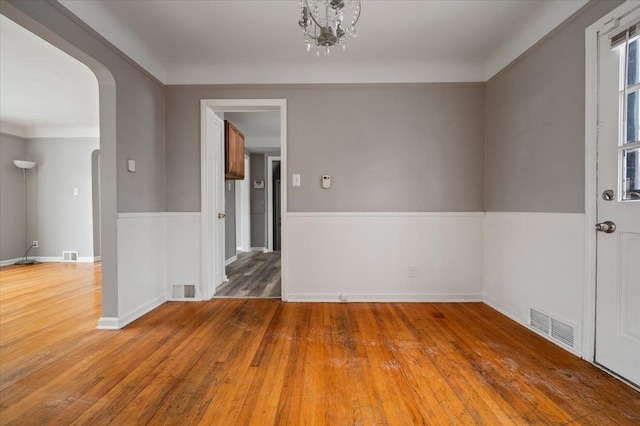 empty room with hardwood / wood-style flooring and an inviting chandelier