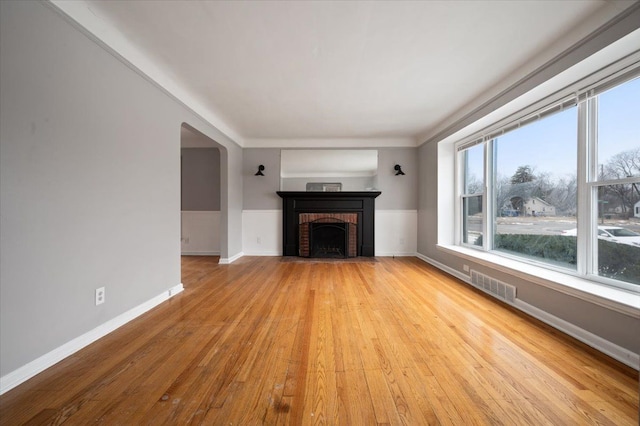 unfurnished living room with a brick fireplace and light wood-type flooring