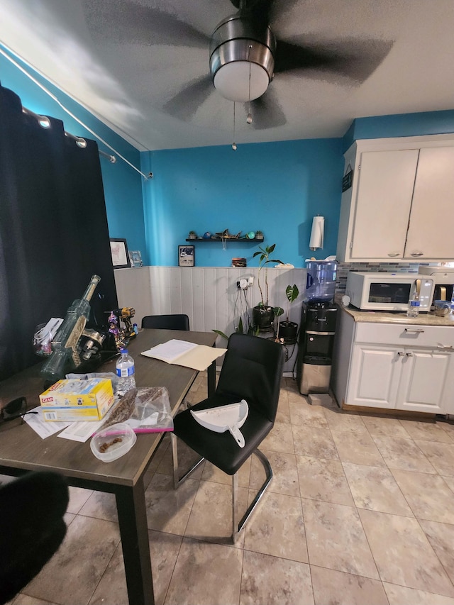 tiled dining space with ceiling fan and a textured ceiling