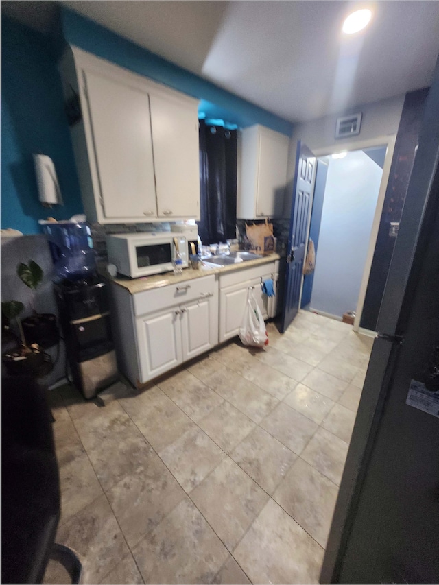 kitchen with light tile patterned floors, sink, and white cabinets