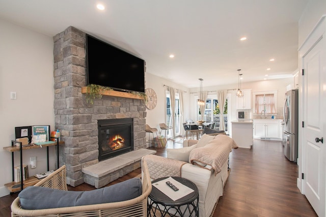 living room featuring a fireplace, dark wood-type flooring, and sink