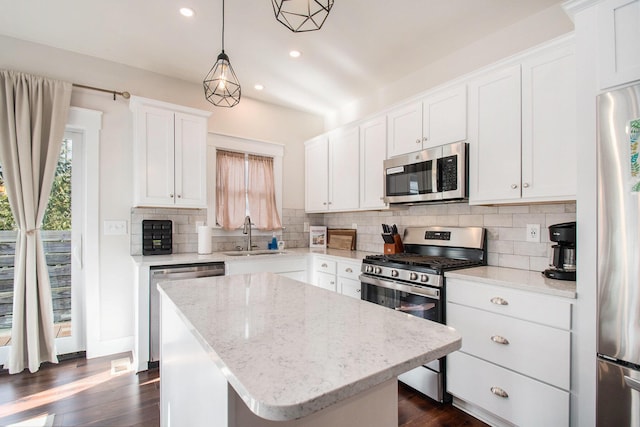 kitchen featuring sink, hanging light fixtures, stainless steel appliances, white cabinets, and a kitchen island