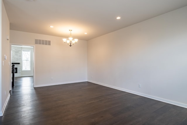 spare room featuring recessed lighting, visible vents, baseboards, dark wood-style floors, and an inviting chandelier