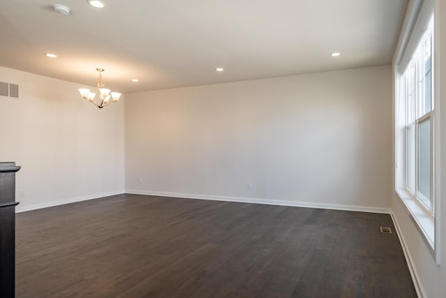 unfurnished room with dark wood-style floors, recessed lighting, baseboards, and an inviting chandelier