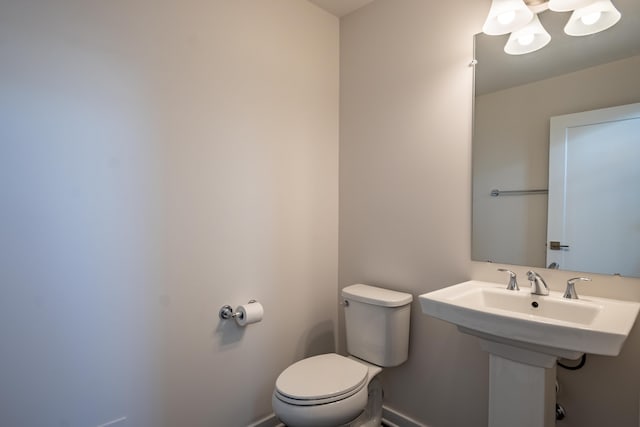 bathroom featuring toilet, baseboards, and a sink