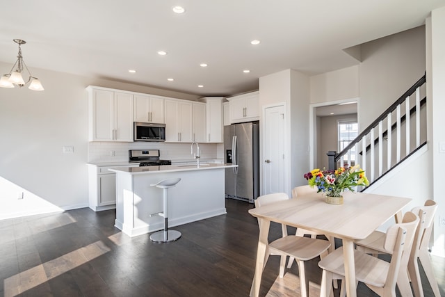 kitchen with stainless steel appliances, dark wood-style flooring, a sink, light countertops, and backsplash