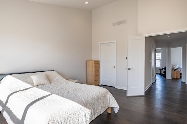 bedroom featuring recessed lighting, dark wood-style flooring, visible vents, and a high ceiling