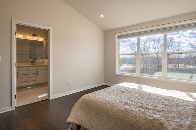 bedroom with connected bathroom, a sink, baseboards, vaulted ceiling, and dark wood finished floors