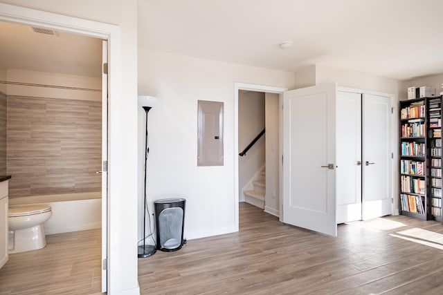 interior space with electric panel, visible vents, ensuite bath, light wood-style flooring, and a closet