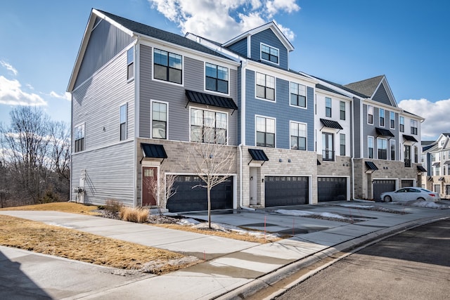 multi unit property featuring a garage, a residential view, and driveway