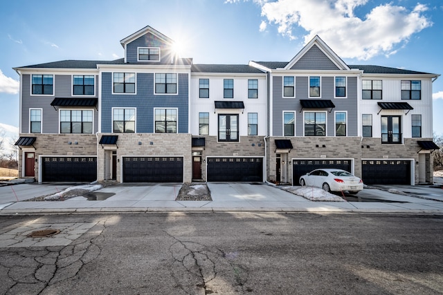 townhome / multi-family property with an attached garage, a standing seam roof, and concrete driveway