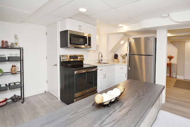 kitchen featuring light hardwood / wood-style flooring, stainless steel appliances, white cabinets, a drop ceiling, and sink