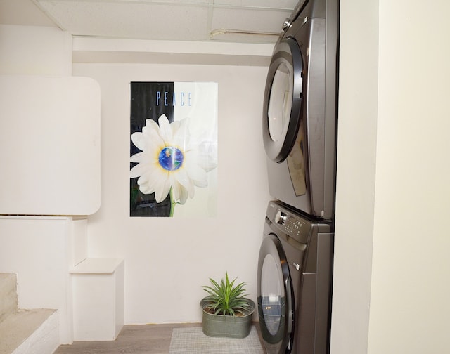 laundry room with light hardwood / wood-style flooring and stacked washer / drying machine