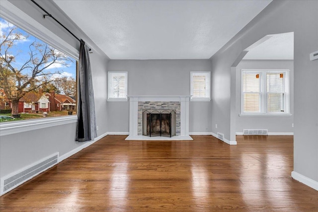 unfurnished living room featuring plenty of natural light and dark hardwood / wood-style floors