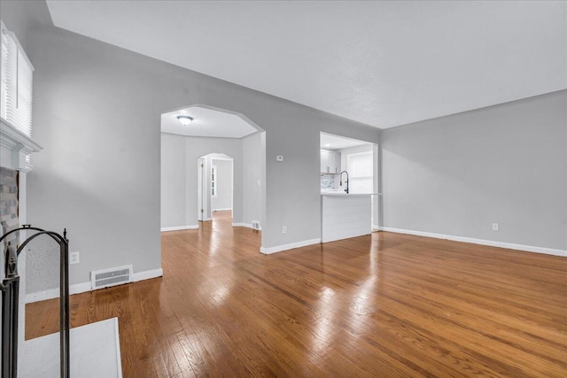 unfurnished living room featuring wood-type flooring, sink, and a fireplace