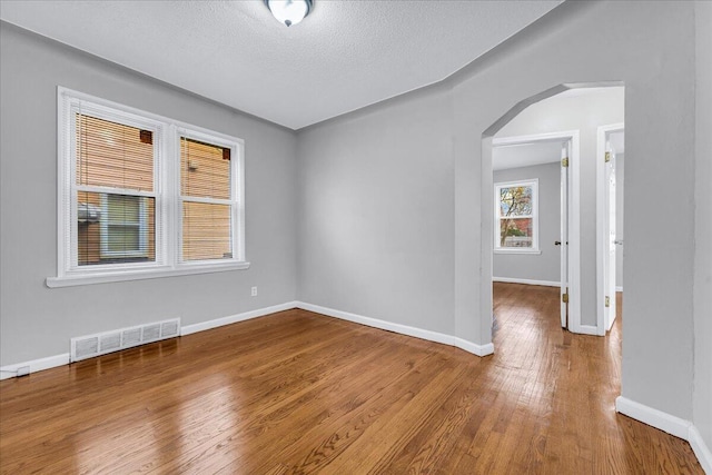 spare room featuring wood-type flooring and a textured ceiling