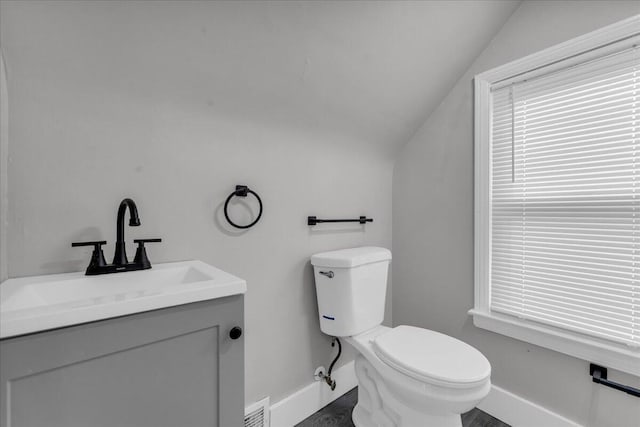 bathroom with lofted ceiling, vanity, and toilet