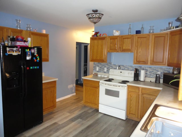 kitchen featuring tasteful backsplash, sink, hardwood / wood-style flooring, electric range, and black refrigerator with ice dispenser