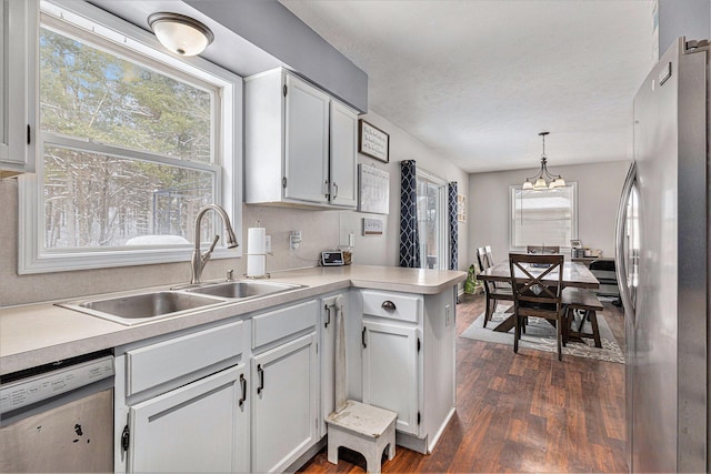 kitchen featuring sink, stainless steel refrigerator, dishwasher, hanging light fixtures, and dark hardwood / wood-style floors