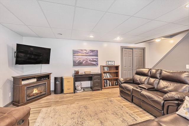 living room featuring light hardwood / wood-style flooring and a drop ceiling