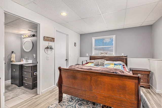 bedroom with light hardwood / wood-style flooring and a drop ceiling