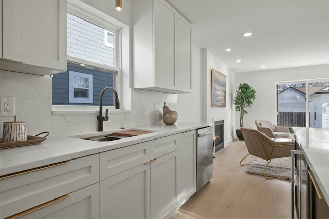 kitchen with white cabinetry, dishwasher, sink, and tasteful backsplash