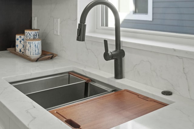 details featuring light stone counters, sink, and tasteful backsplash