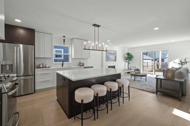 kitchen featuring pendant lighting, sink, appliances with stainless steel finishes, white cabinets, and a kitchen island