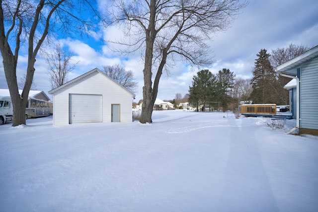 yard layered in snow featuring an outbuilding and a garage