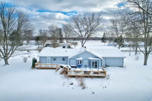 snow covered rear of property featuring a wooden deck and a garage