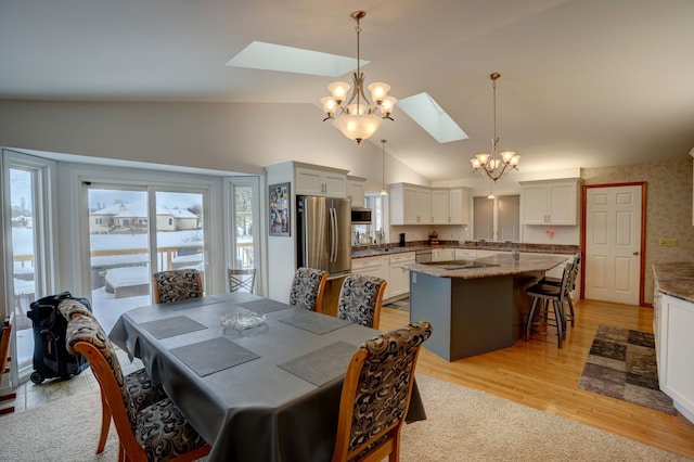 dining space featuring light hardwood / wood-style flooring, an inviting chandelier, and lofted ceiling with skylight