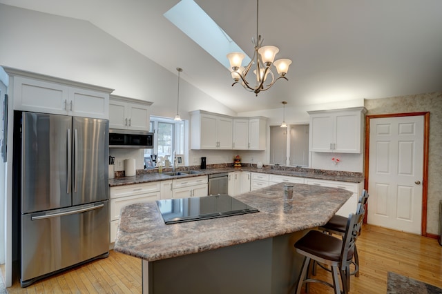 kitchen with sink, stainless steel appliances, a kitchen island, and decorative light fixtures