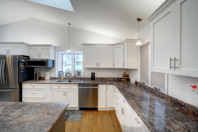 kitchen featuring sink, light wood-type flooring, stainless steel appliances, white cabinets, and hanging light fixtures