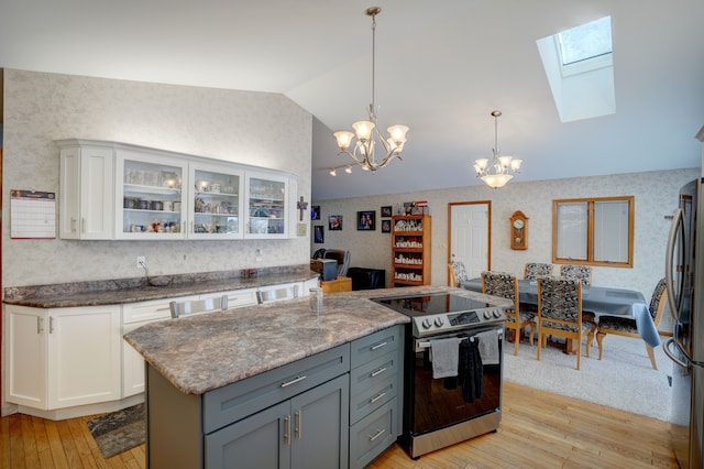 kitchen featuring white cabinetry, pendant lighting, light hardwood / wood-style floors, stainless steel appliances, and lofted ceiling with skylight