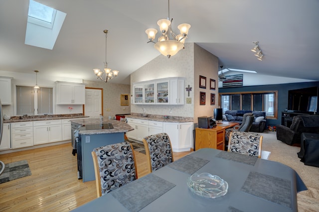 dining area with lofted ceiling with skylight, a chandelier, and light hardwood / wood-style flooring