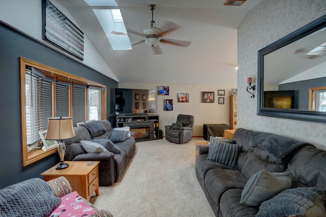 carpeted living room with vaulted ceiling with skylight and ceiling fan