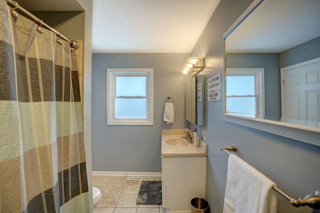 bathroom featuring plenty of natural light, vanity, toilet, and tile patterned floors