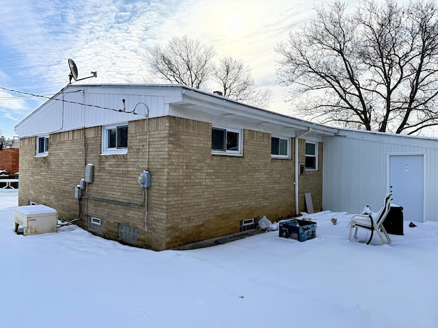 view of snow covered exterior featuring brick siding