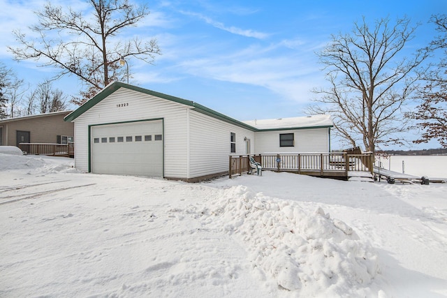 view of front facade with a garage, a wooden deck, and an outbuilding