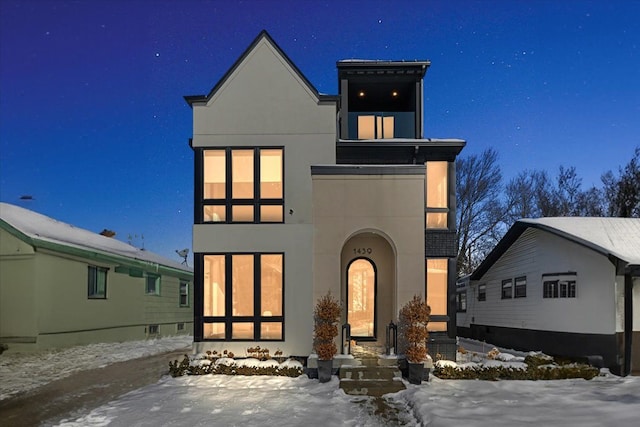 snow covered back of property with stucco siding