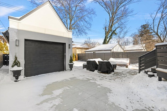 snow covered garage with a detached garage and fence