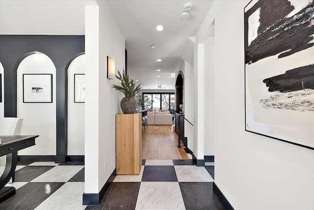 hallway with arched walkways, baseboards, and recessed lighting