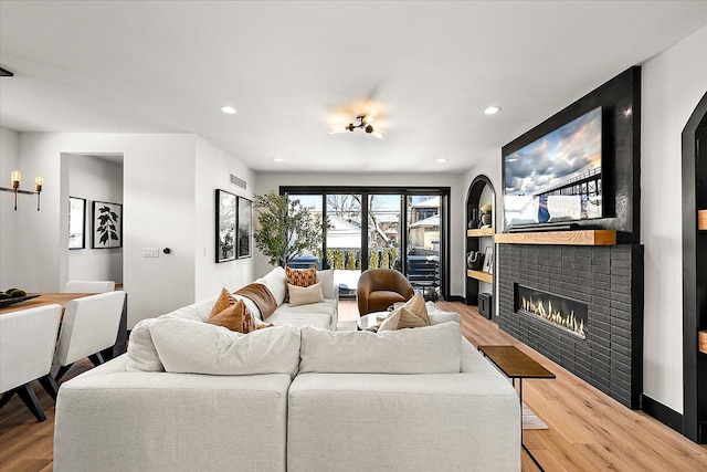 living area with recessed lighting, visible vents, wood finished floors, and a glass covered fireplace